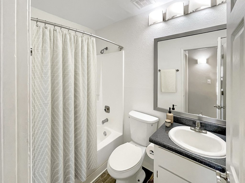 A white bathroom with a toilet, sink, and shower.